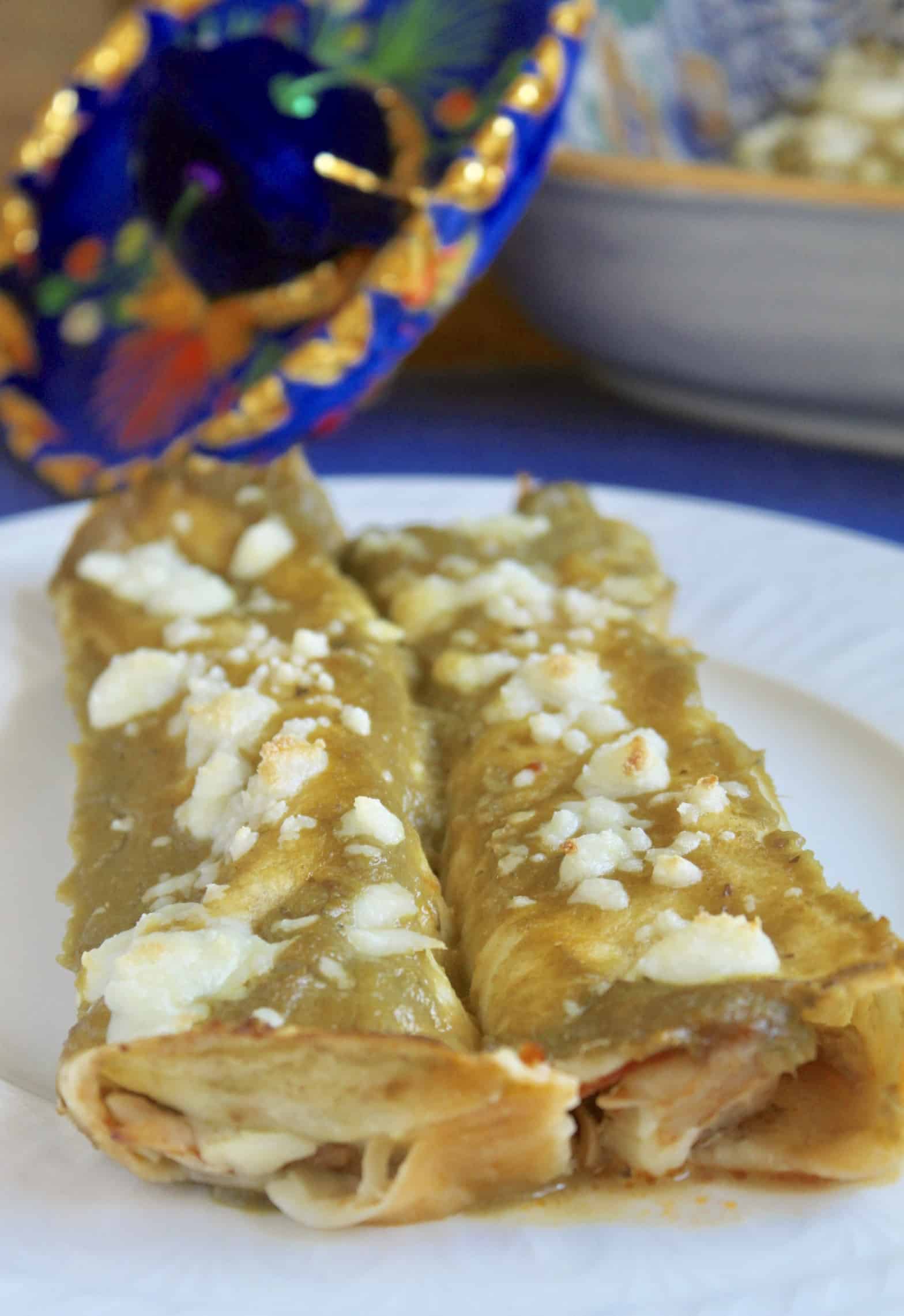 Green chicken enchiladas on a plate with a Mexican hat