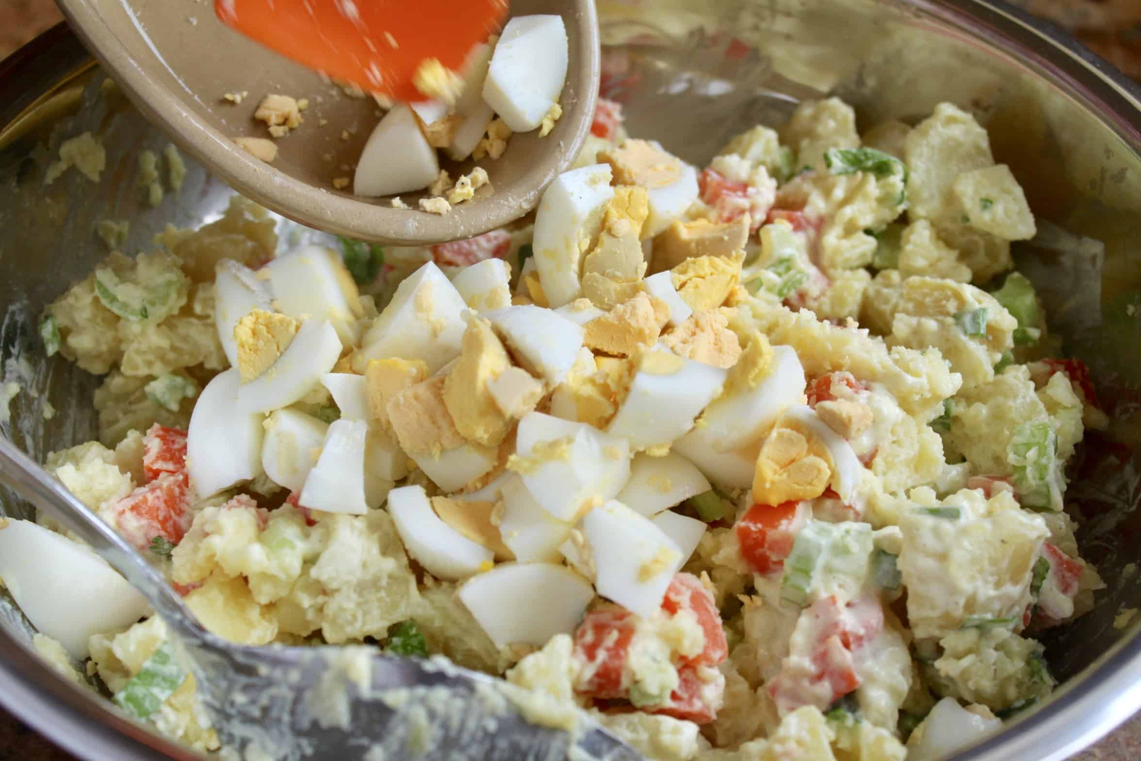 adding eggs to Korean potato salad