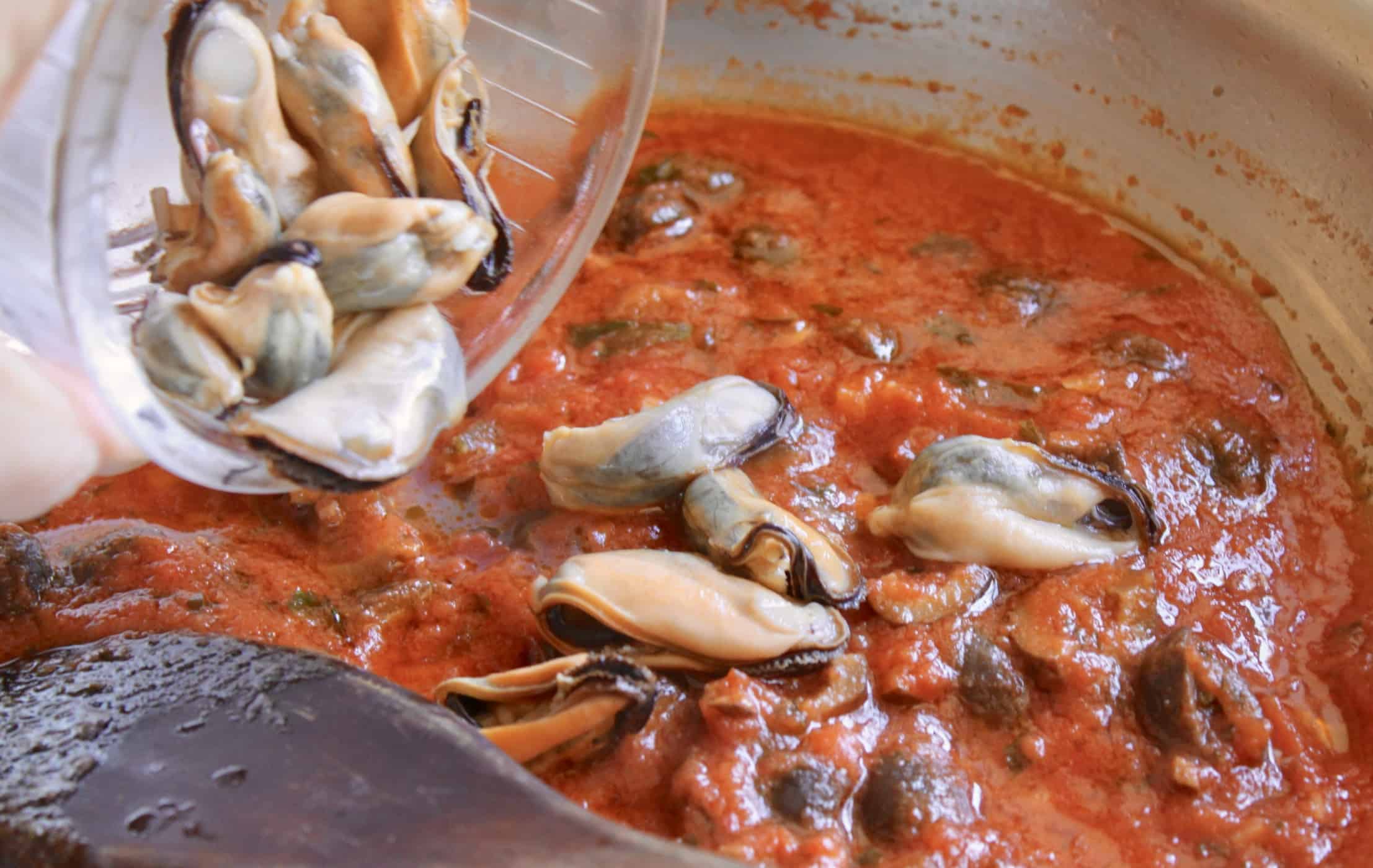 adding mussels to the sauce