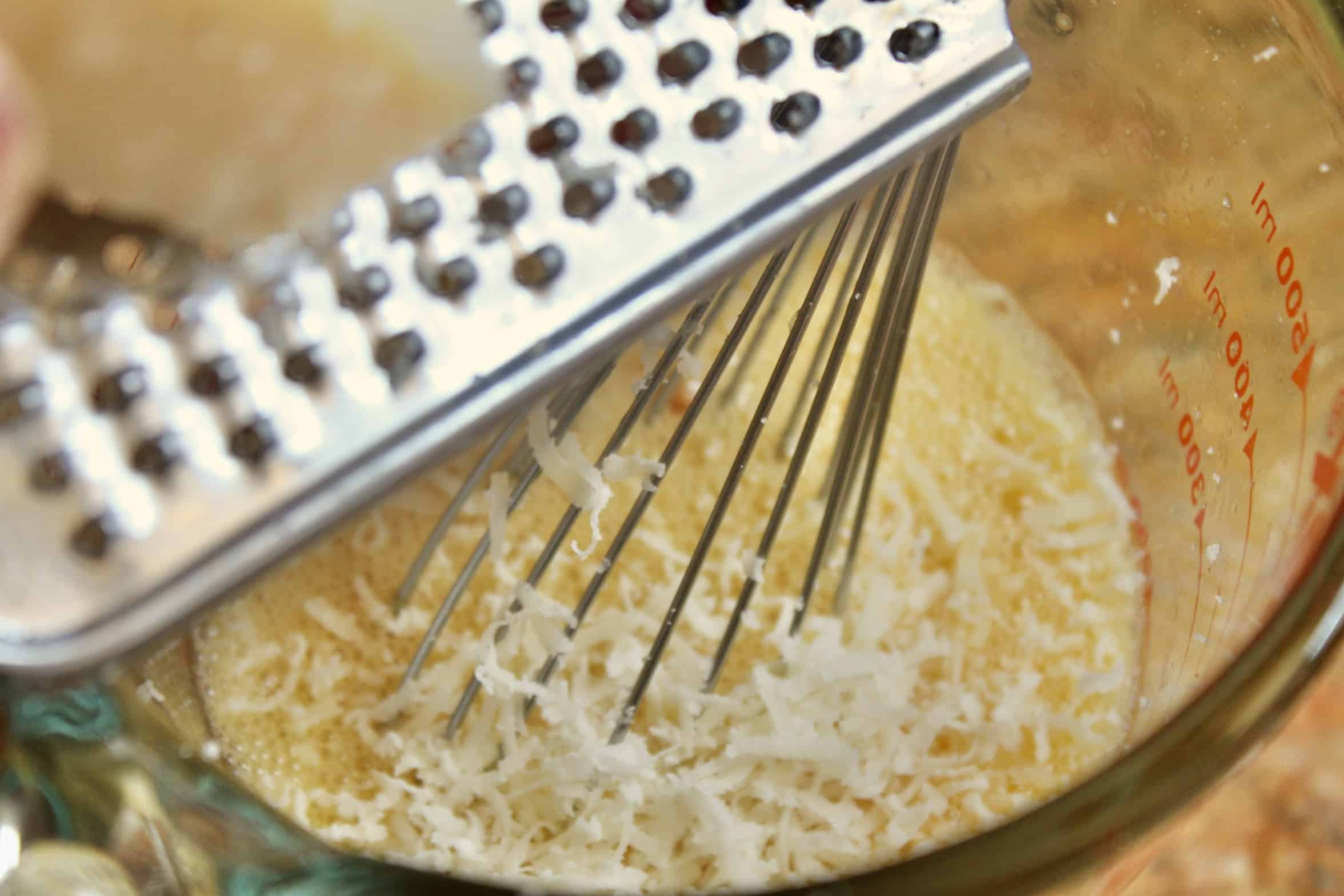 adding grated cheese to beaten eggs