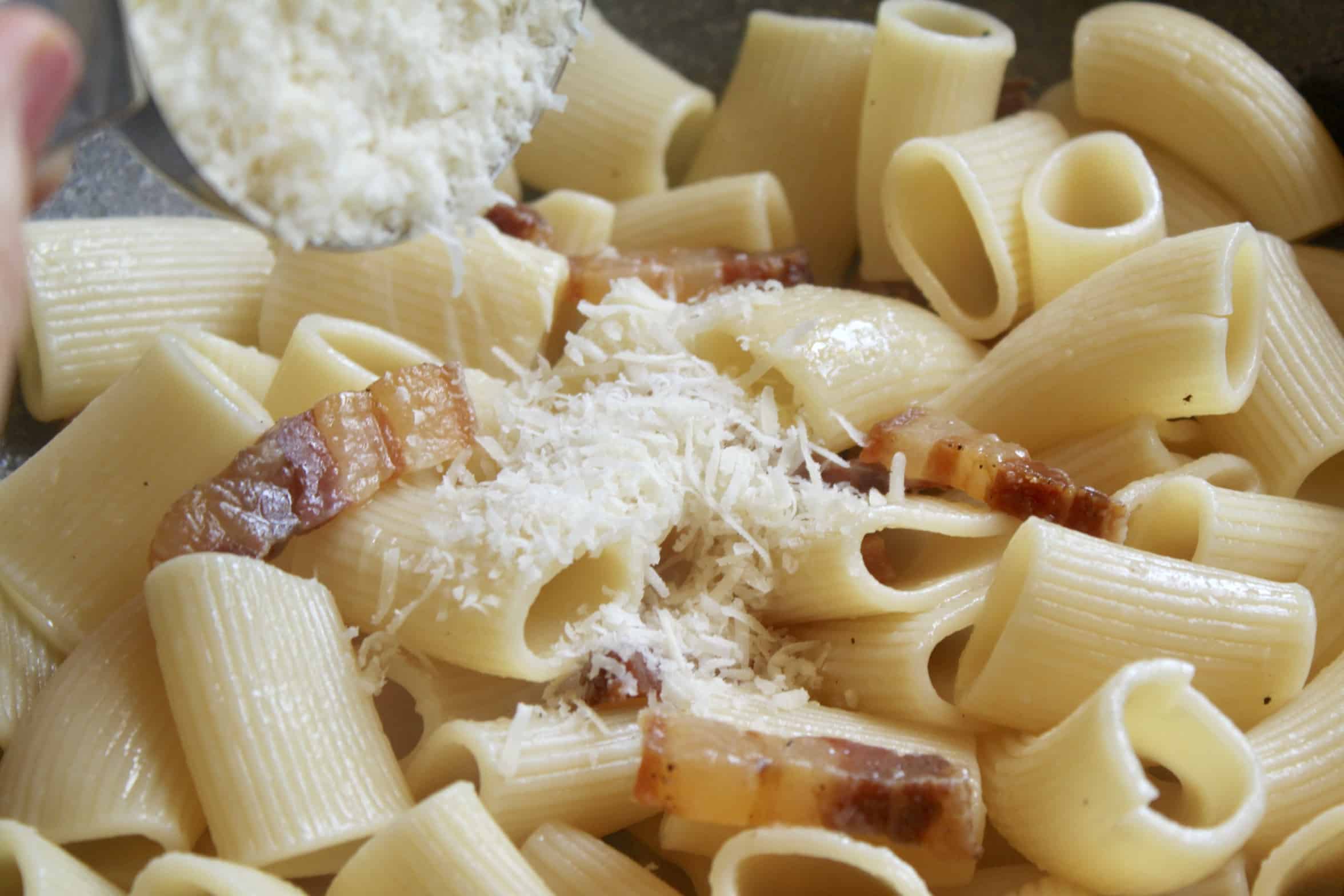 adding Parmigiano to the pancetta pasta