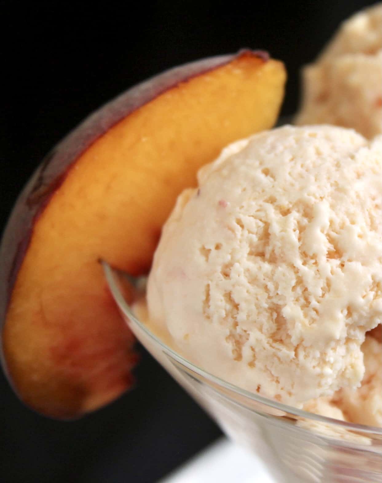 close up of peach ice cream and slice of peach