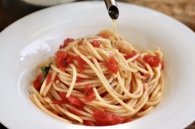 drizzling extra virgin olive oil on pasta