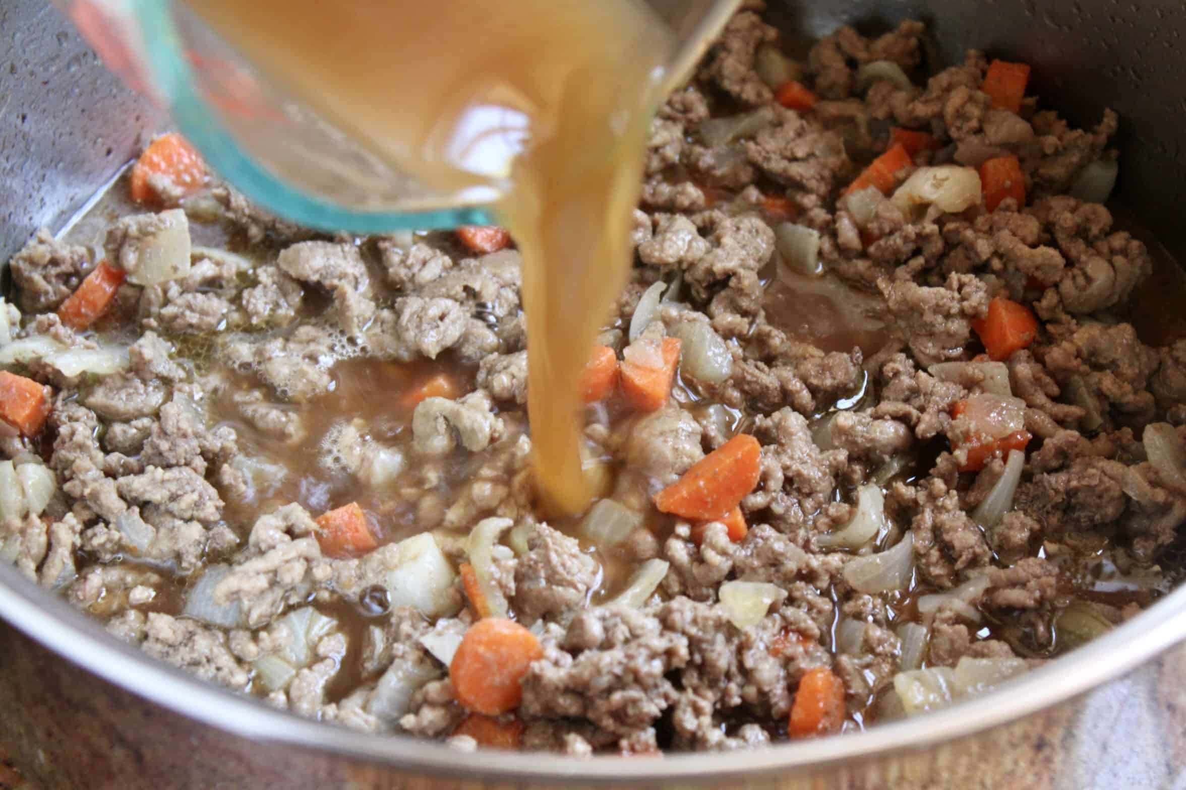 adding beef stock to pot