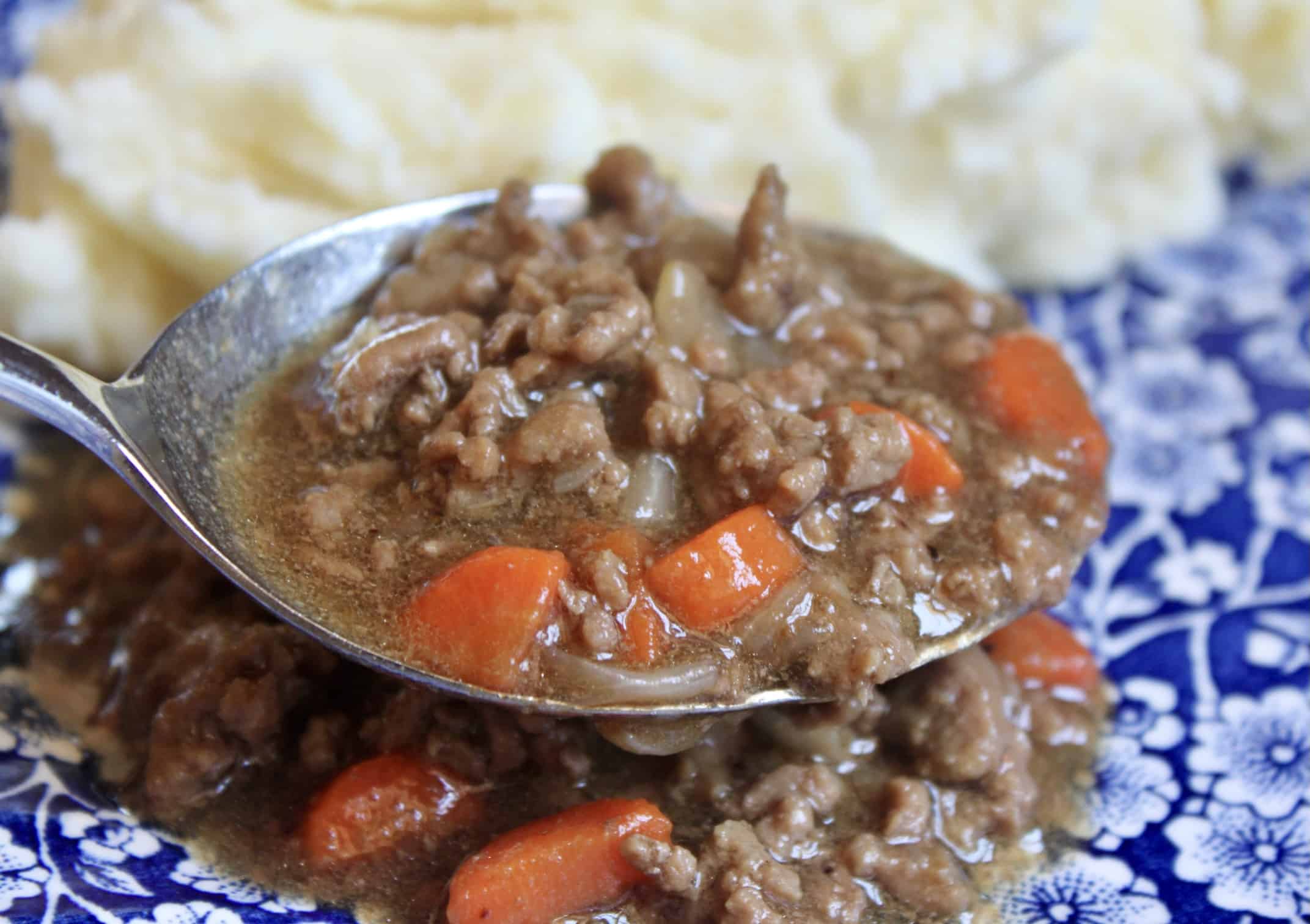 spooning out mince onto a plate with potatoes