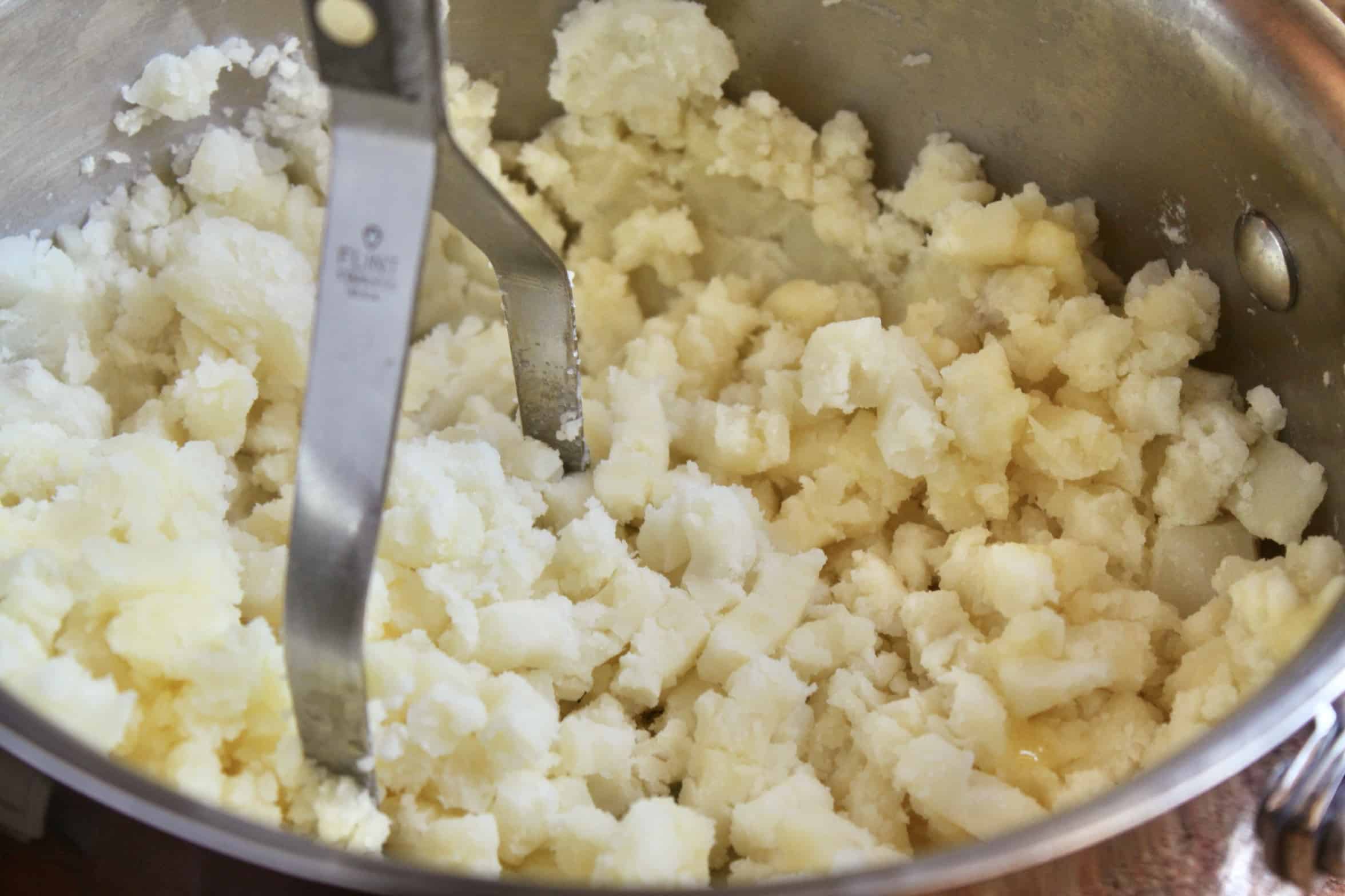 mashing potatoes in a pot