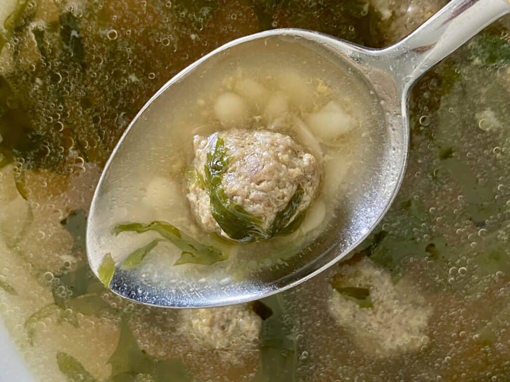 mini meatball on a spoon over Italian wedding soup