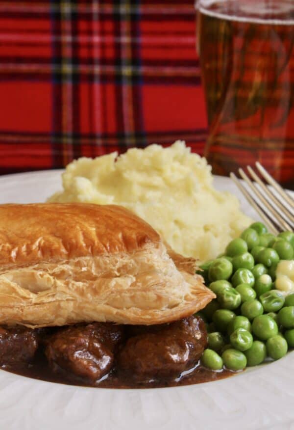 scottish steak pie, potatoes and peas with tartan background