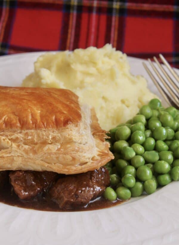 scottish steak pie, potatoes and peas with tartan background