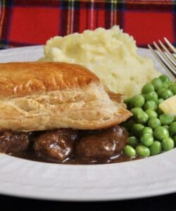 scottish steak pie, potatoes and peas with tartan background