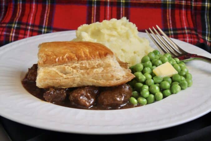 scottish steak pie, potatoes and peas with tartan background