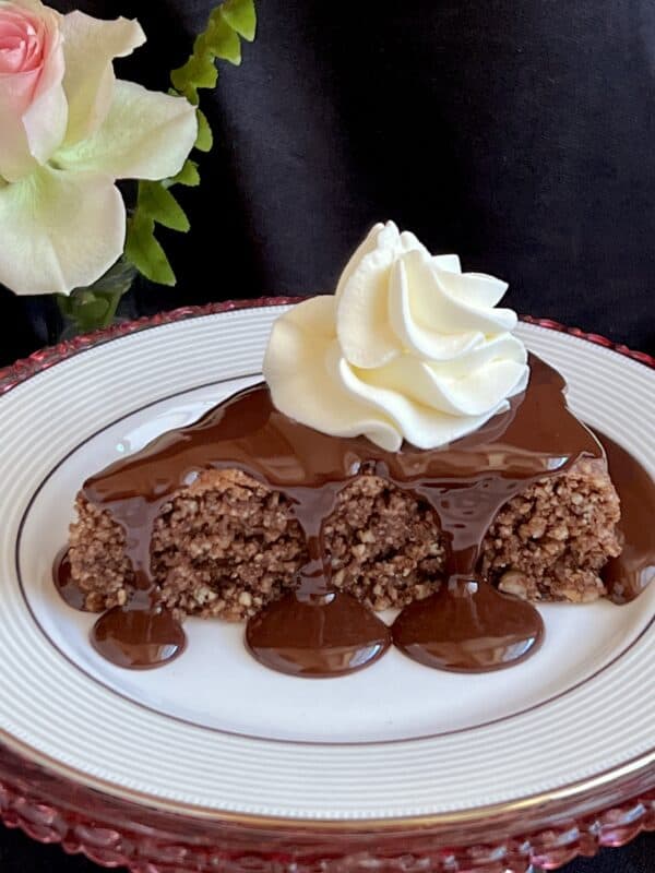 chocolate sauce poured over a slice of cake with whipped cream.