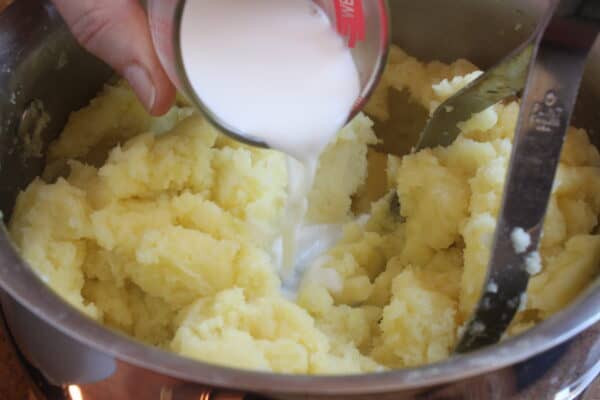 adding milk and cream to potatoes