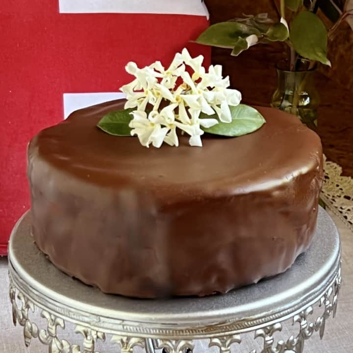 chocolate biscuit cake with flowers on top on a cake plate