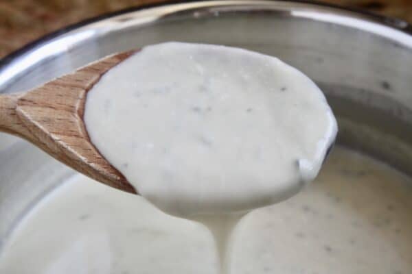 gorgonzola sauce pouring from a wooden spoon