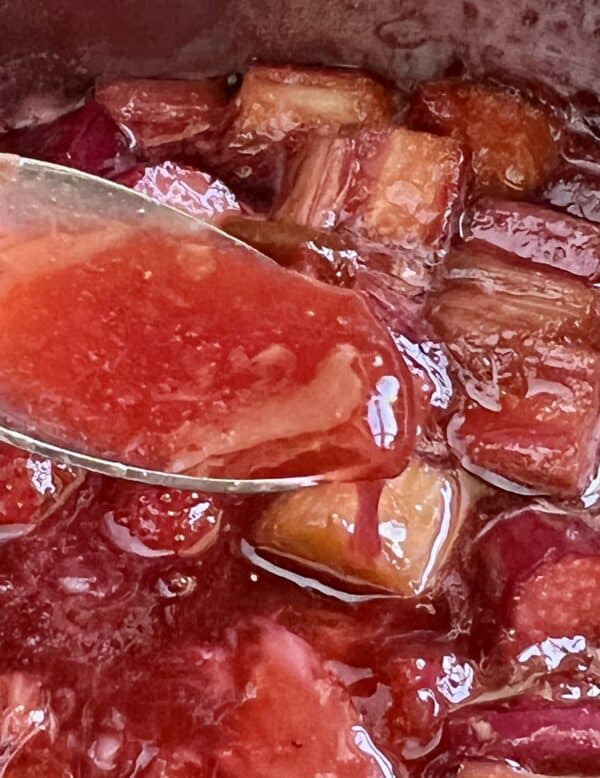 Strawberry rhubarb pie filling in a spoon.