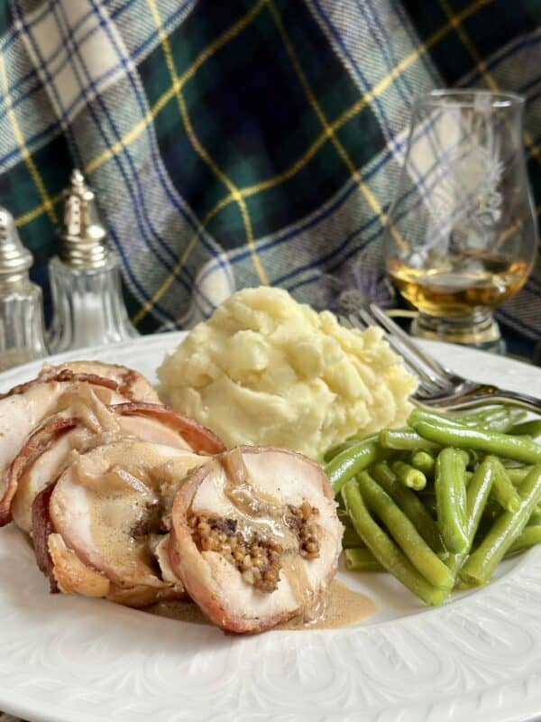 Balmoral chicken dinner on a plate with tartan and a dram of whisky