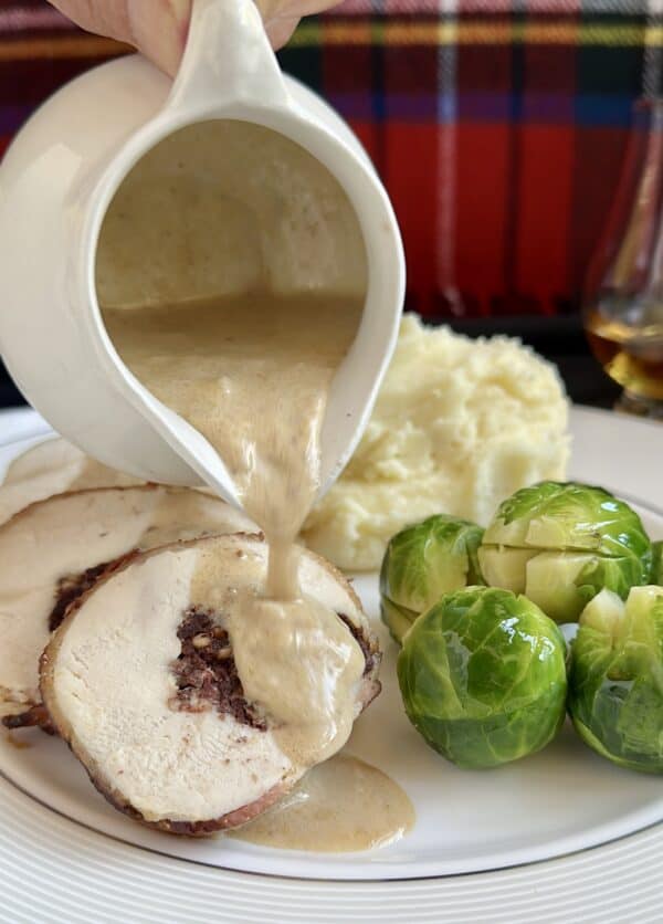 pouring whisky sauce on black pudding stuffed chicken