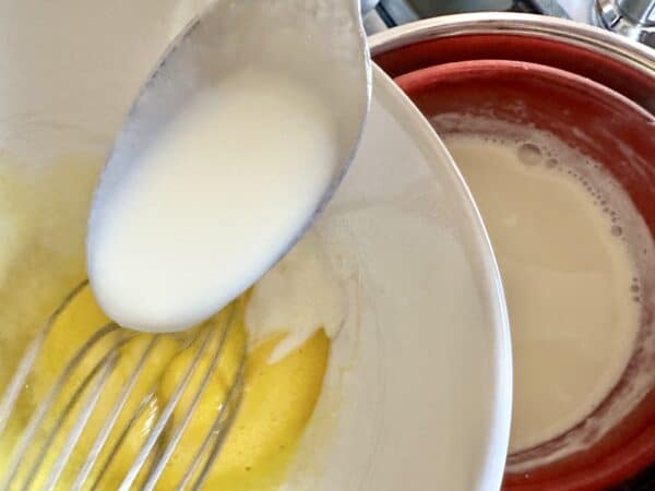 adding hot milk and cheese to egg yolks