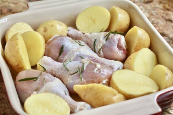 preparing chicken drumsticks in the oven and potatoes in a baking dish