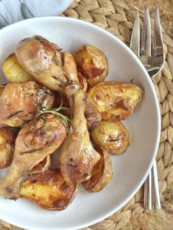 chicken drumsticks in the oven and potatoes in a bowl from above