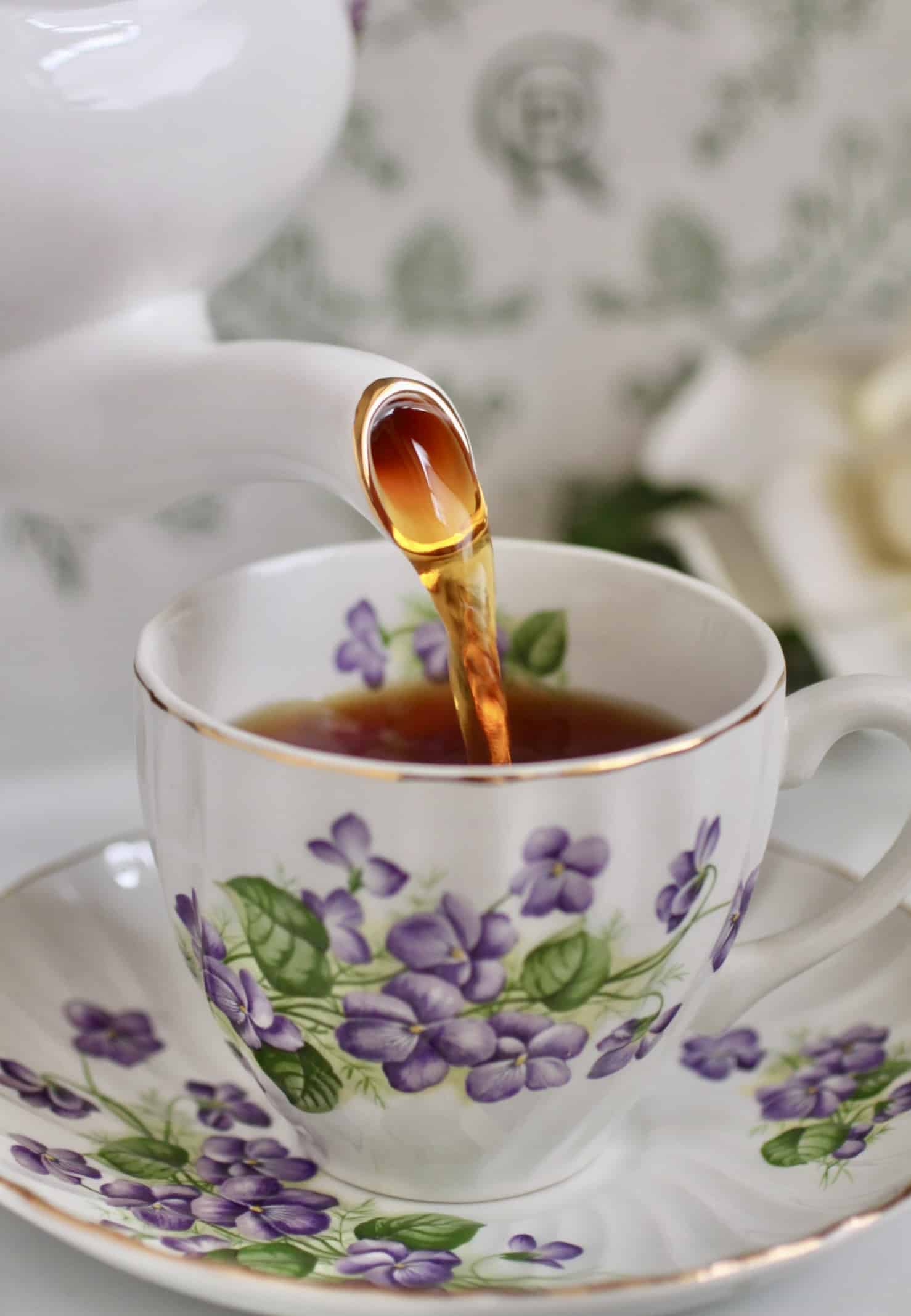 pouring loose leaf tea into a violet cup