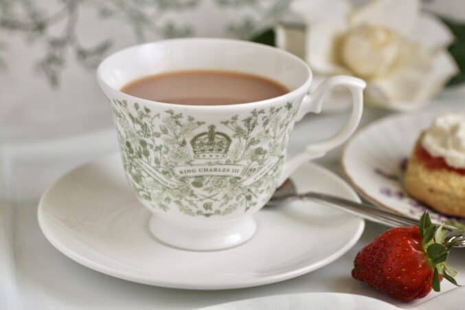 coronation cup of tea with a saucer and a strawberry nearby