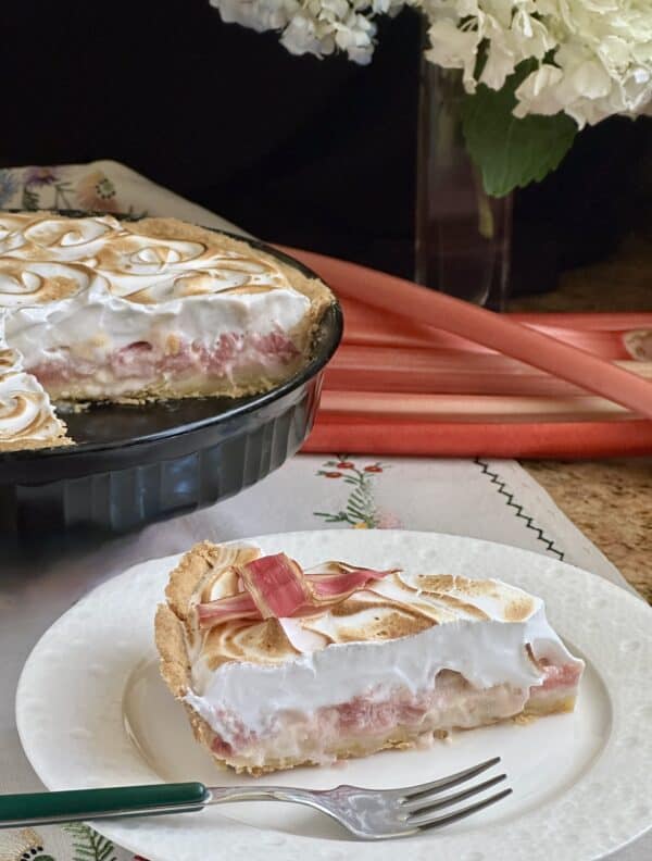 Slice of rhubarb tart with cut tart in background.