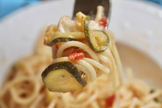 forkful of spaghetti with zucchini and tomatoes
