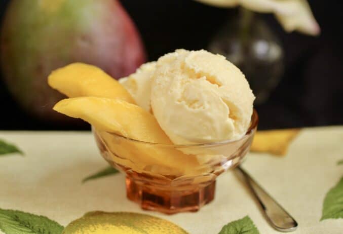 mango ice cream in a bowl with mango slices