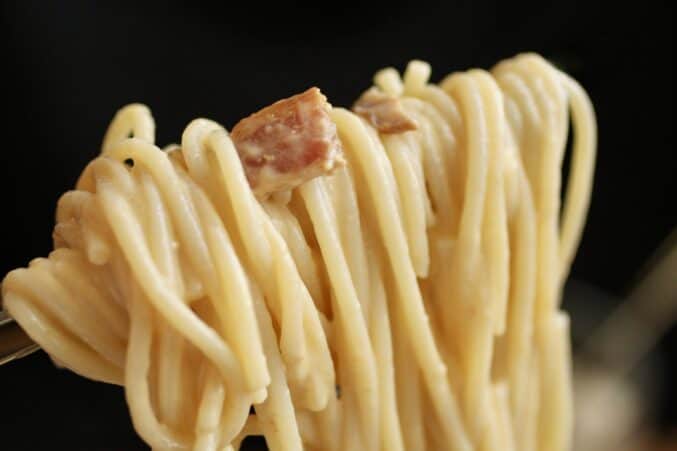 egg and bacon pasta on tongs