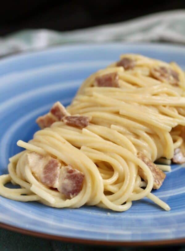 pasta with egg and bacon on a blue plate