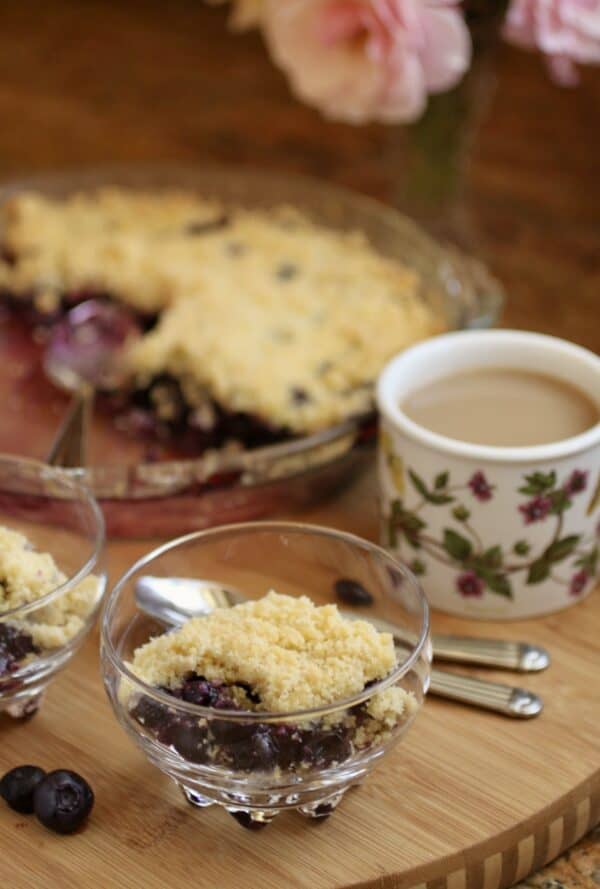 blueberry crumble in dish with cup of tea