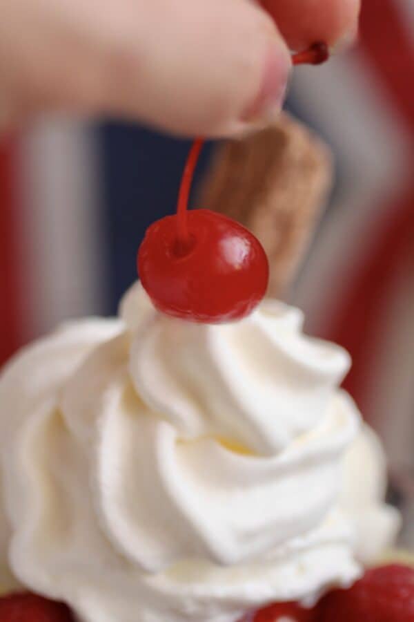 adding cherry on top of whipped cream