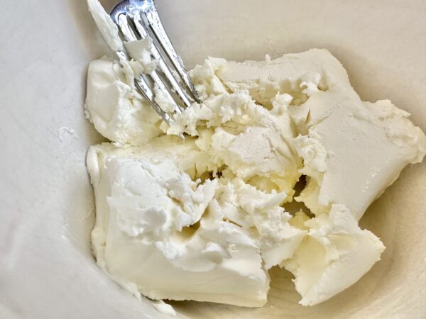forking cream cheese in a bowl