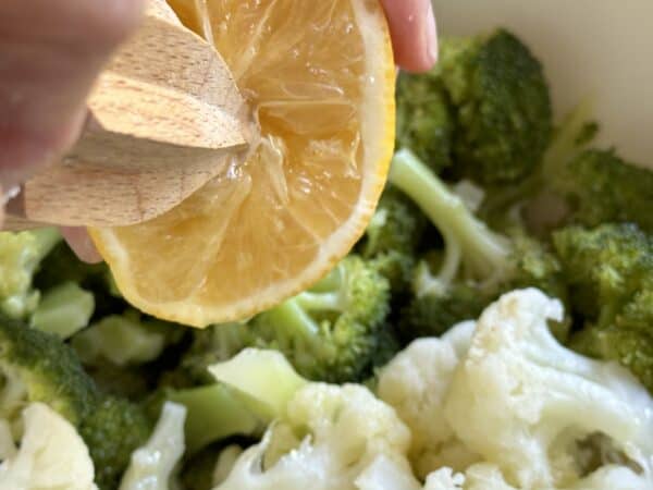 squeezing lemon into the broccoli and cauliflower salad