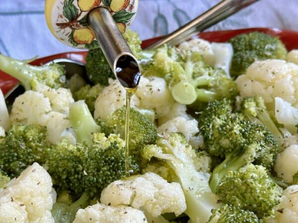 pouring oil over broccoli and cauliflower salad
