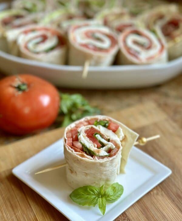 Caprese pinwheel sandwich with tomato and more sandwiches in background