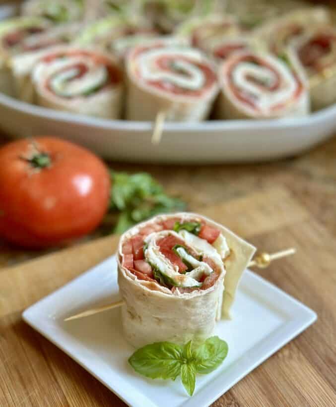 Italian pinwheels with tomato and more sandwiches in background