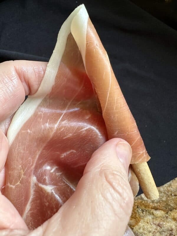 rolling prosciutto on a breadstick