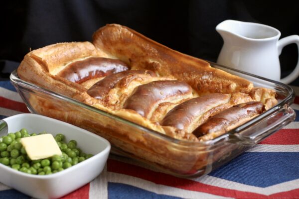 toad in the hole in a pan with peas and a jug of gravy