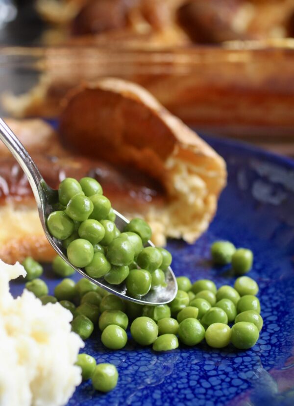 adding peas to plate of toad in the hole