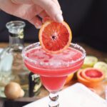 putting blood orange slice in margarita