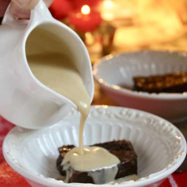 pouring brandy sauce on Christmas pudding in bowl