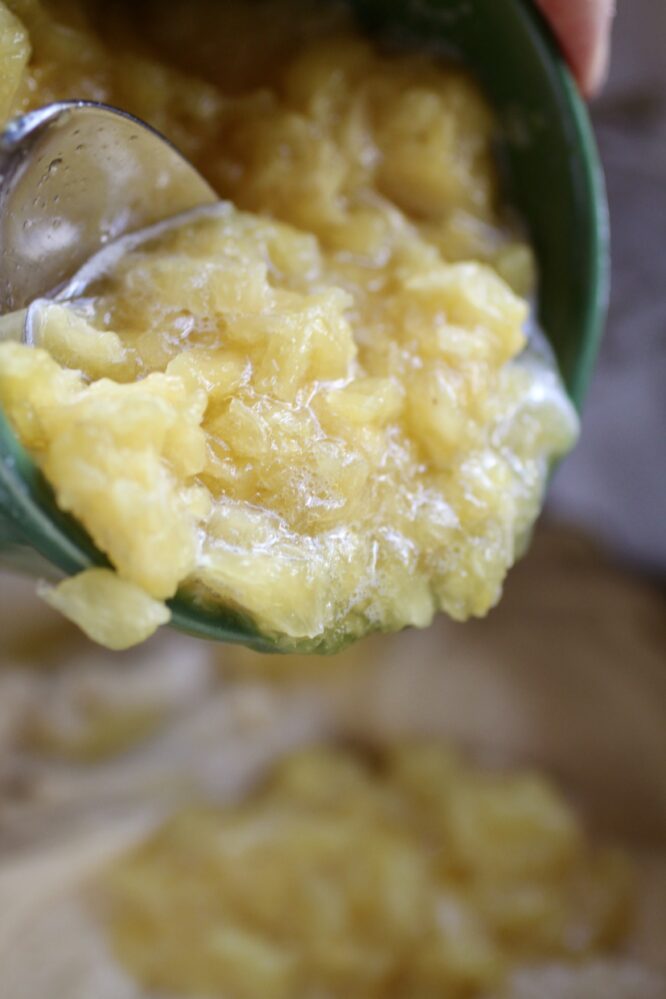 pouring pureed pineapple into cake batter