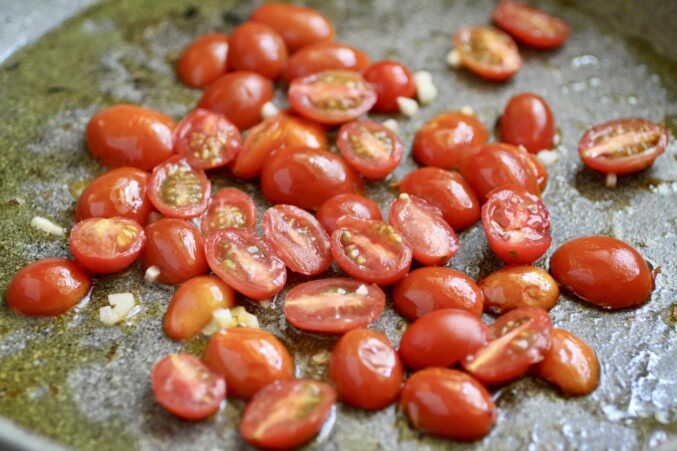 adding tomatoes to a pan