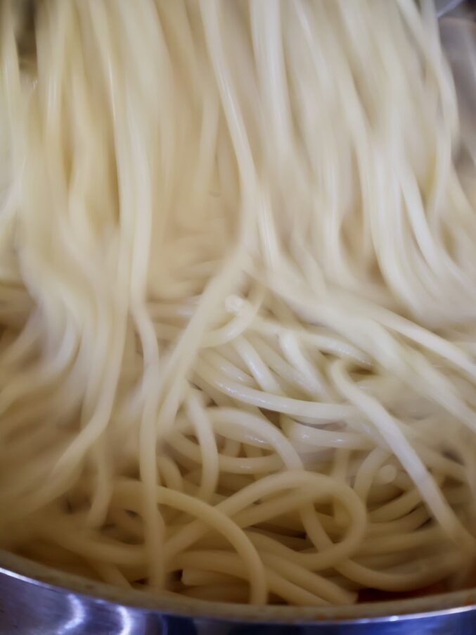 adding pasta to sauce