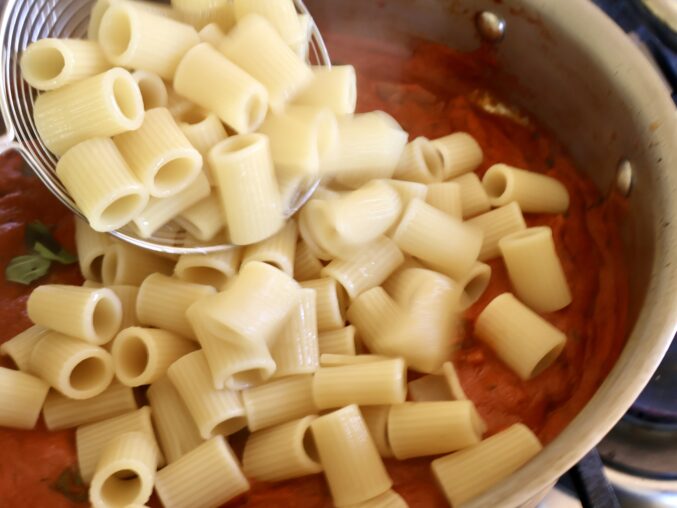 adding rigatoni to sugo