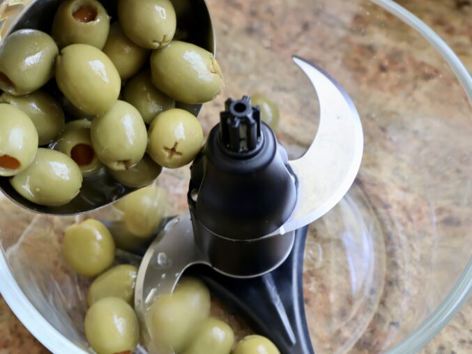 adding green olives to make olive tapenade recipe