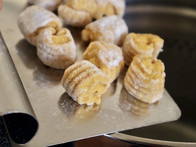 scooping pumpkin gnocchi into pot
